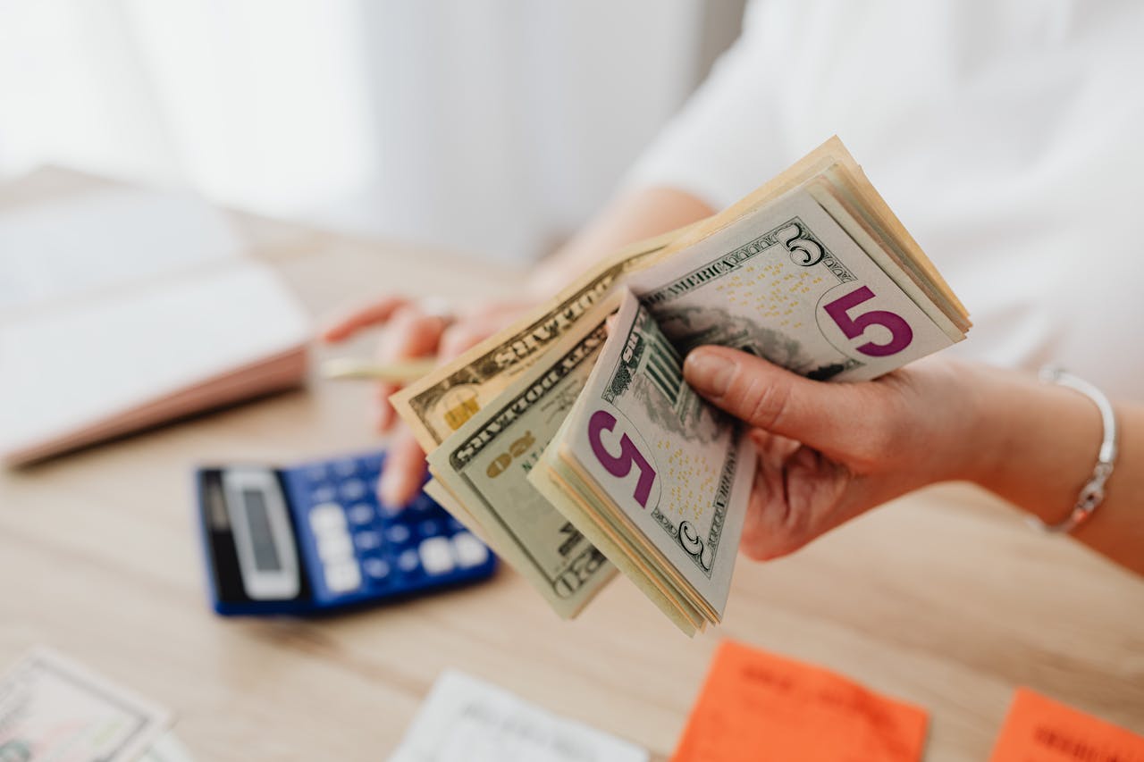 a person holding cash with a calculator